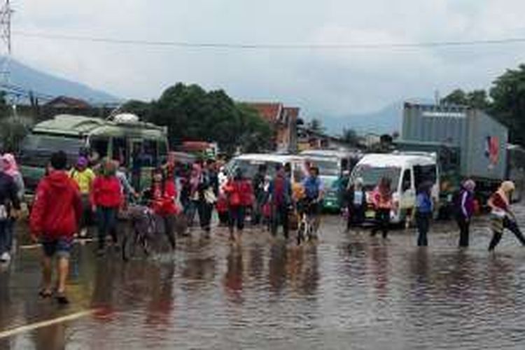 Puluhan buruh pabrik menyebrangi Jalan Rancaekek. Mereka berharap banjir segera surut agar aktivitas berjalan normal kembali, Selasa (1/11/2016).