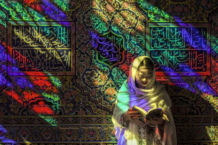 Ilustrasi seorang perempuan sedang membaca Al Quran di masjid Nasir Al-Mulk, Iran.