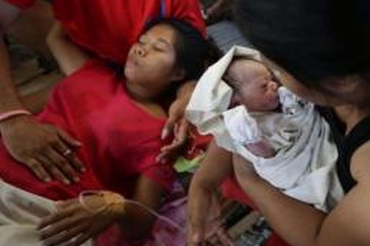Emily Ortega (21) beristirahat dengan infus di tangannya, setelah melahirkan bayi Bea Joy di sebuah tempat penampungan pengungsi korban topan Haiyan di Tacloban, Filipina. Nama Bea Joy diambil dari nama nenek Emily yang masih hilang setelah kediaman mereka disapu ombak raksasa.