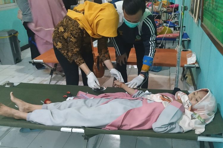 Seorang pasien korban keracunan makanan massal sedang mendapatkan penanganan tim medis di Puskesmas Bantargadung, Sukabumi, Jawa Barat, Kamis (12/9/2019).