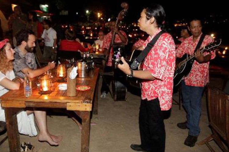 Grup musik menghibur turis asing saat makan malam di pinggir pantai Jimbaran, Bali, Jumat (21/6/2013). Kawasan Jimbaran merupakan salah satu tempat tujuan wisatawan selama berlibur di Bali, sejumlah tempat wisata seperti Jimbaran fish market dan Pura Uluwatu berada dekat dengan kawasan ini.  
