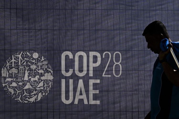 Seorang pekerja berjalan melewati logo COP28 menjelang KTT iklim PBB tersebut di Dubai, Uni Emirat Arab (UEA), Selasa (28/11/2023). Sekjen PBB mendesak para pemimpin dunia untuk mengambil tindakan tegas guna mengatasi perubahan iklim yang semakin memburuk ketika mereka berkumpul di KTT COP28 mulai Kamis (30/11/2023).