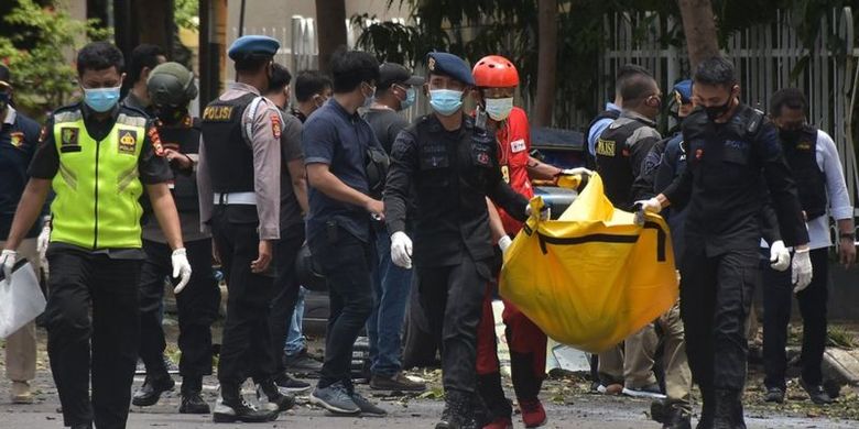Petugas kepolisian mengangkat kantong jenazah berisi bagian tubuh dari terduga pelaku bom bunuh diri di depan Gereja Katedral Makassar, Sulawesi Selatan, hari Minggu (28/03).