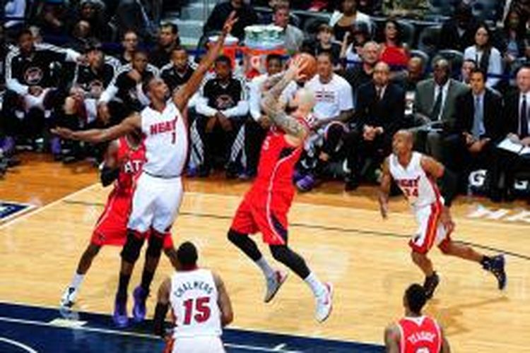 Pebasket Atlanta Hawks, Pero Antic (tengah #6) berusaha memasukkan bola di depan pemain Miami Heat, Chris Bosh (#6) pada laga yang berlangsung di Phillips Arena, Senin (20/01/2014).