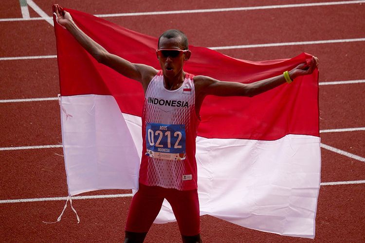 Pelari Indonesia Agus Prayogo mengibarkan bendera Merah Putih seusai memasuki garis finish nomor marathon putra SEA Games 2019 di Stadion Atletik New Clark City, Clark, Filipina, Jumat (6/12/2019). Agus berhasil menyumbangkan medali emas pertama cabang atletik setelah menyelesaikan lomba sepanjang 42km itu dalam waktu dua jam 26 menit 48 detik.