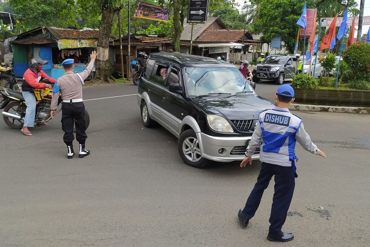 Polisi dan petugas Dinas Perhubungan (Dishub) memutarbalikkan mobil yang akan menuju Baturraden saat pemberlakuan gajil genap dari pertigaan Pabuaran, Purwokerto, Kabupaten Banyumas, Jawa Tengah, Sabtu (25/9/2021).