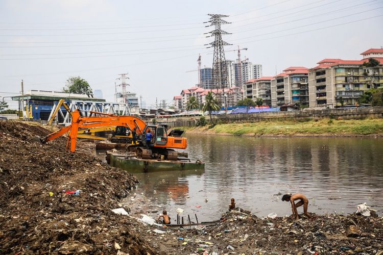 Sejumlah anak-anak mencari sampah berupa besi saat pekerja mengeruk lumpur menggunakan ekskavator di Kanal Banjir Barat (KBB) sungai Ciliwung di Tanah Abang, Jakarta Pusat, Senin (11/9/2017). Pengerukan lumpur dilakukan untuk memperlancar aliran air sungai serta mengantisipasi datangnya musim hujan yang mengakibatkan banjir yang kerap terjadi di Jakarta.