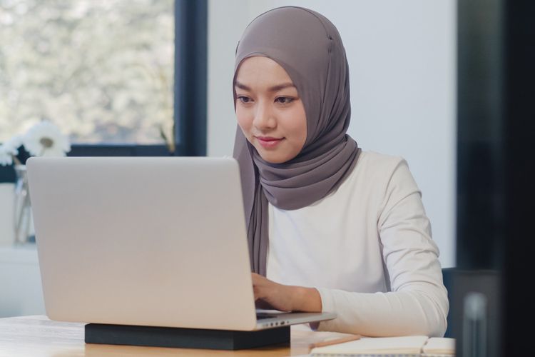 Ilustrasi wanita Muslim sedang bekerja menggunakan laptop.