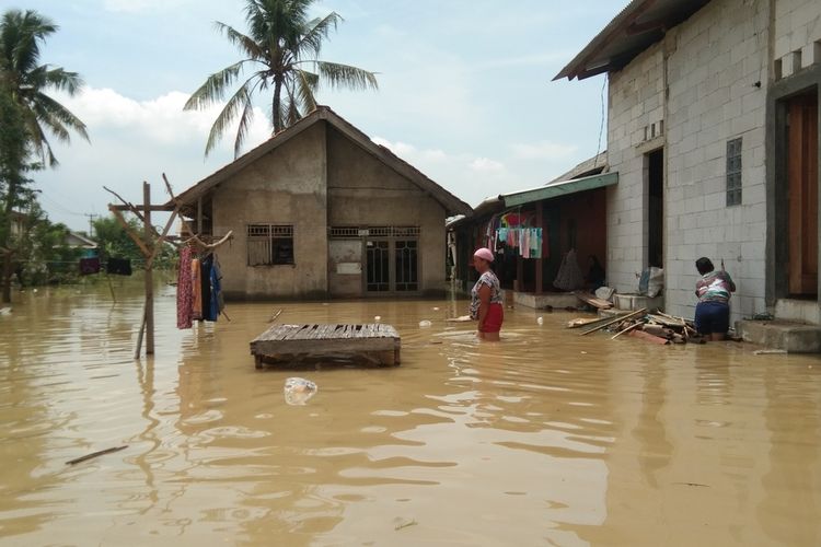 Warga Kampung Pengasinan, Desa Karangligar, Kecamatan Telukjambe Barat, Kabupaten Karawang tengah beraktivitas di sela banjir, Senin (8/11/2021).