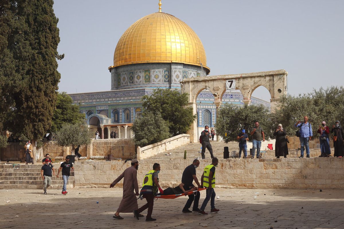 Warga Palestina mengevakuasi seorang pria yang terluka selama bentrokan dengan pasukan keamanan Israel di depan Masjid Kubah Batu di kompleks Masjid Al Aqsa di Kota Tua Yerusalem Senin, 10 Mei 2021. 