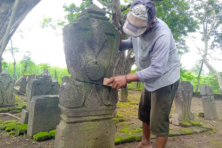 Juru Pelihara Situs Nduro, Sugeng (47), saat membersihkan lumut yang menempel di nisan pada kompleks pemakaman kuno Dusun Nanggungan, Desa Watudandang, Kecamatan Prambon, Kabupaten Nganjuk, Jawa Timur, Rabu (13/3/2024)