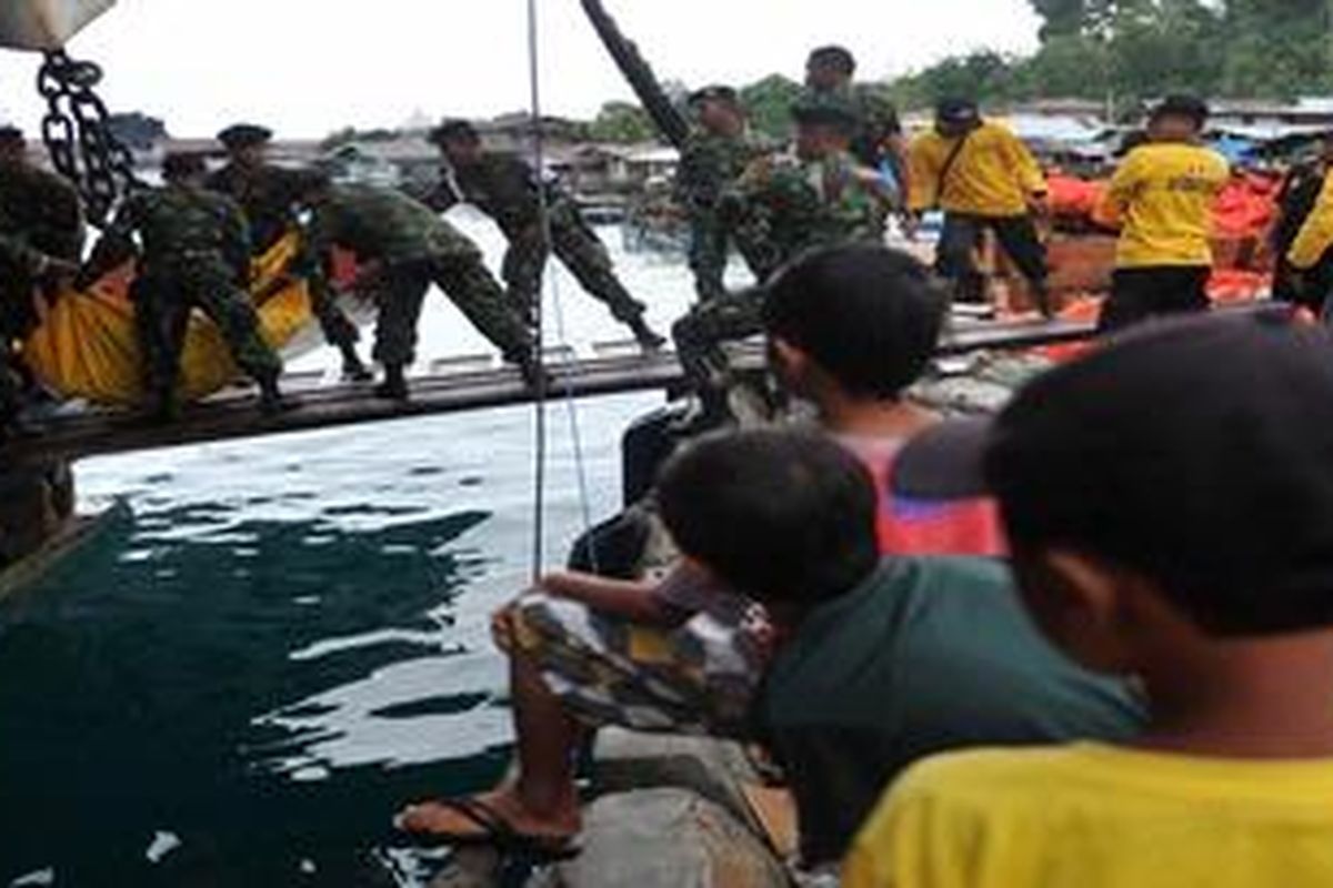 Three local children observe Indonesian military personel unload relief goods for tsunami victims in the Mentawai islands at the port of Sikakap village in the Metawai islands, West Sumatra, on October 30, 2010. More than 130 people listed as missing have been found alive on high ground on a remote Indonesian island that was devastated by a tsunami five days ago, an official said.