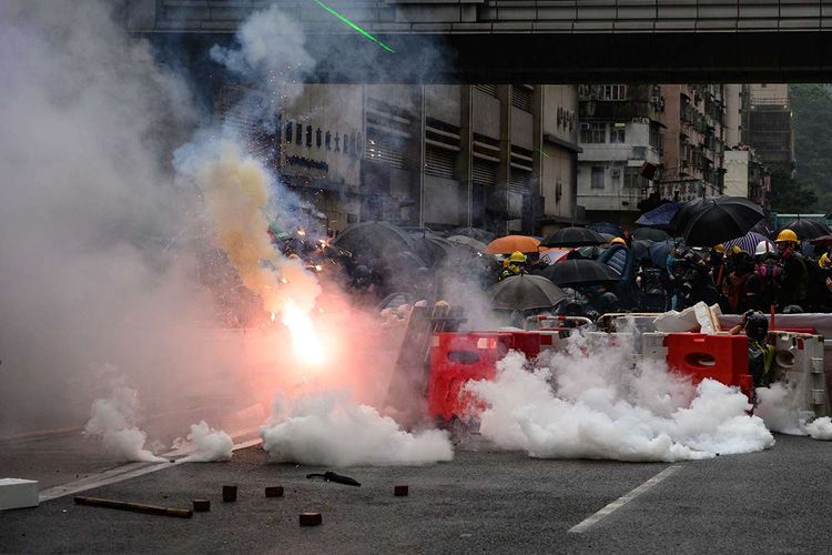 Polisi menembakkan gas air mata ke arah pengunjuk rasa pro-demokrasi, saat terjadi bentrokan di Tseun Wan, Hong Kong, Minggu (25/8/2019). Aksi protes telah bergulir selama 3 bulan terakhir di Hong Kong, dimulai ketika Kepala Eksekutif Hong Kong Carrie Lam memperkenalkan undang-undang yang bisa mengekstradisi kriminal ke China daratan.