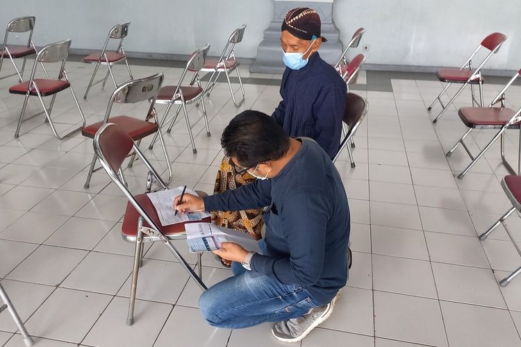 Suratijo seorang abdi dalem Keraton Yogyakarta saat dibantu menulis form oleh pemuda yang ada di sekitar JEC, Kamis (13/1/2022)