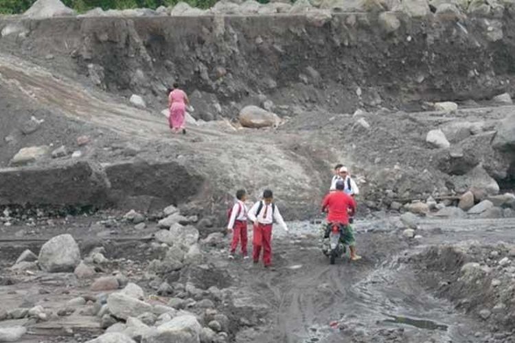 Siswa dan warga melintasi jalur alternatif untuk bisa menyeberangi Sungai Regoyo di Dusun Sumberlangsep, Desa Jugosari, Lumajang, Selasa (25/1/2022)