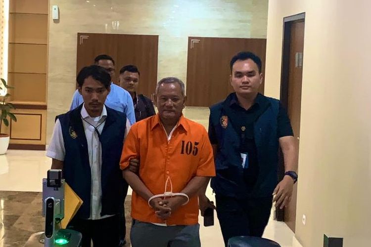 Vigit Waluyo saat berjalan didamping polisi seusai ditahan karena pengaturan skor Liga 2 yang mempertemukan PSS Sleman vs Madura FC pada 2018 silam. Terkini, Vigit Waluyo dindikasikan masih melakukan pengaturan skor di Liga Indonesia musim ini.