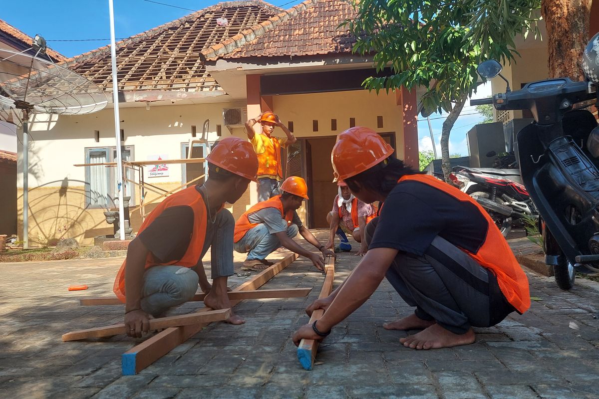 Para pekerja merakit tangga dari kayu untuk digunakan dalam proses renovasi gedung sementara sekolah rakyat. 