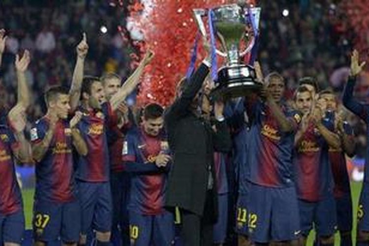 Pelatih Barcelona, Tito Vilanova (kiri) dan bek Barcelona, Eric Abidal, menggenggam trofi La Liga dalam upacara penyerahan di Camp Nou, Minggu (19/5/2013).