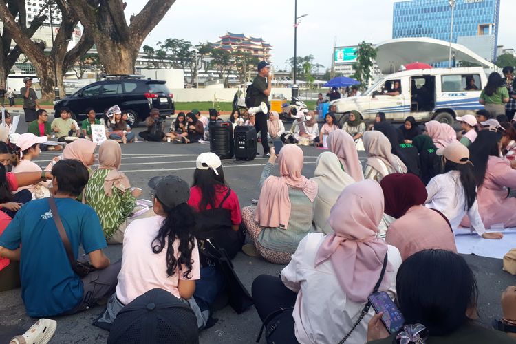 Massa aksi duduk di jalan sembari menyimak orator menyampaikan sejumlah tuntutannya saat unjuk rasa di Jalan Balai Kota, Medan, Sabtu (6/9/2025).