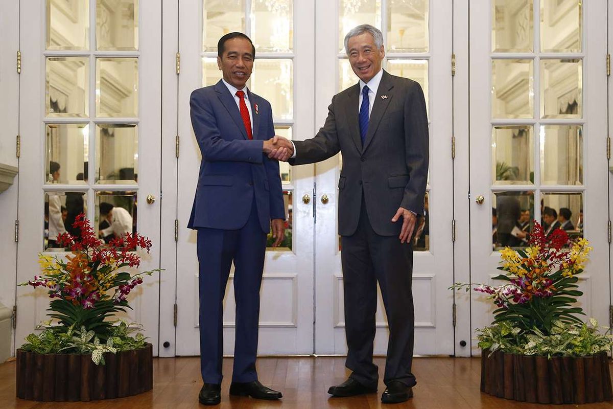 Presiden Joko Widodo (kiri) bersalaman dengan PM Singapura Lee Hsien Loong, di sela kunjungan kerja Jokowi di Singapura, Selasa (8/10/2019). Indonesia dan Singapura kembali berkomitmen untuk memperkuat kerja sama keuangan antara bank sentral kedua negara, yakni pengelolaan likuiditas valas secara bilateral (bilateral liquidity management arrangement).