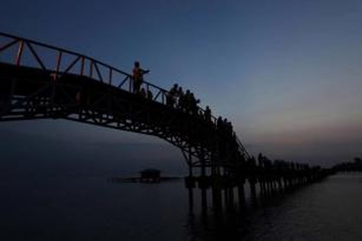 Wisatawan menikmati suasana matahari pagi di Jembatan Cinta yang menghubungkan Pulau Tidung Besar dan Pulau Tidung Kecil, di Kepulauan Seribu.