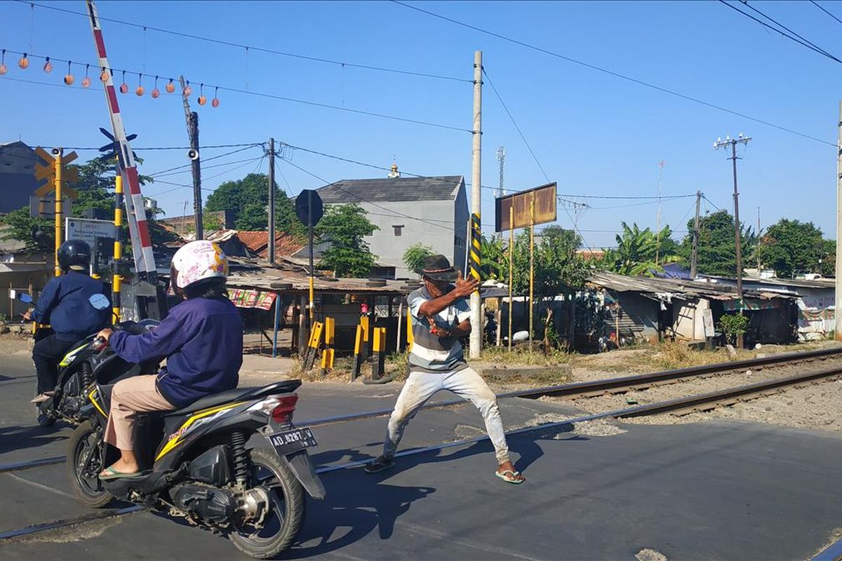 Diryan (55) alias Kopral, penjaga perlintasan sebidang rel kereta api Proyek, Bekasi Timur yang kondang dengan gerakan silatnya tengah melancarkan aksinya, Selasa (23/7/2019).