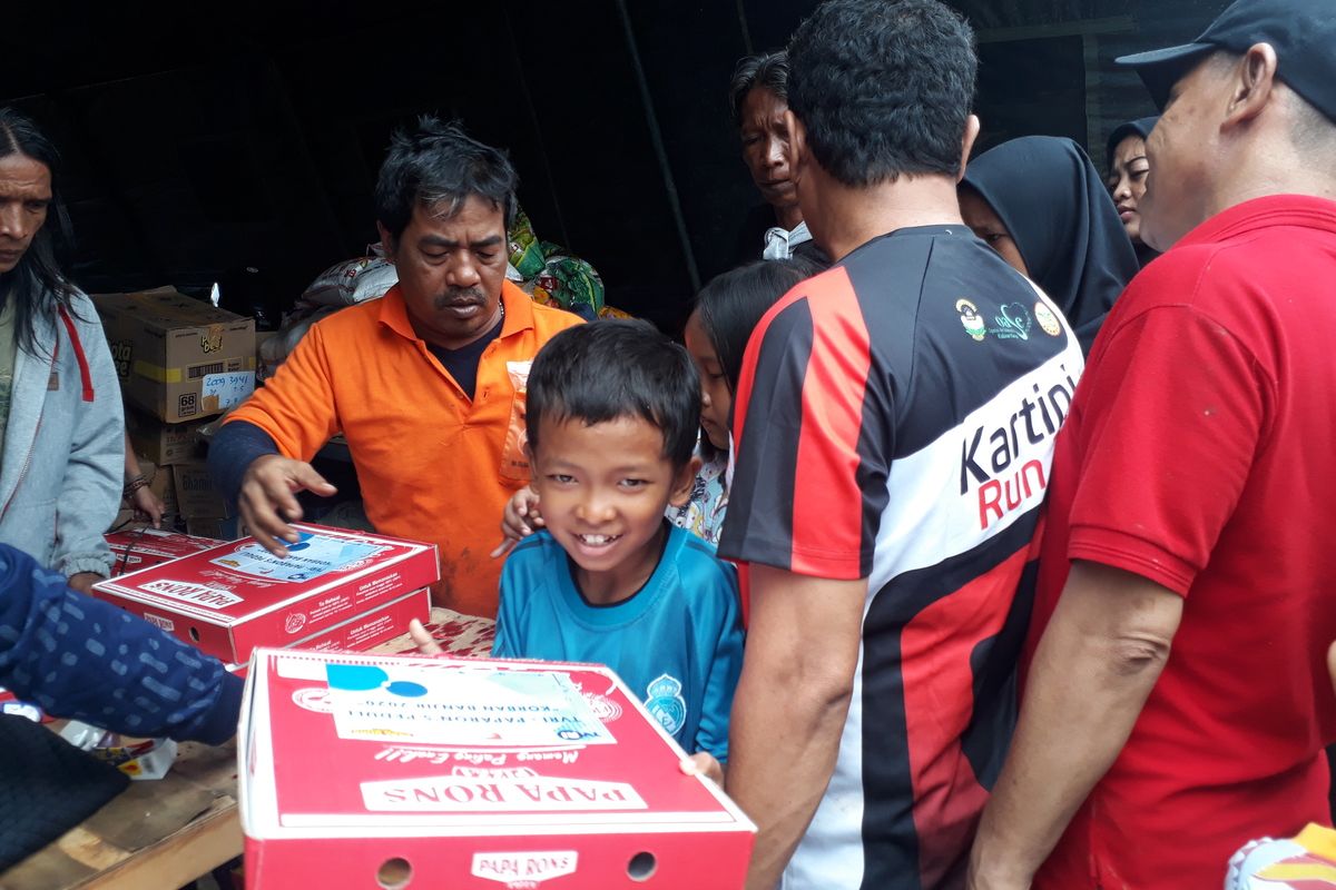 Warga Kampung Pulo, Kelurahan Kampung Melayu, Jatinegara, Jakarta Timur, saat terima bantuan makanan berupa pizza di posko logistik, Jalan Jatinegara Barat, Minggu (5/1/2020).