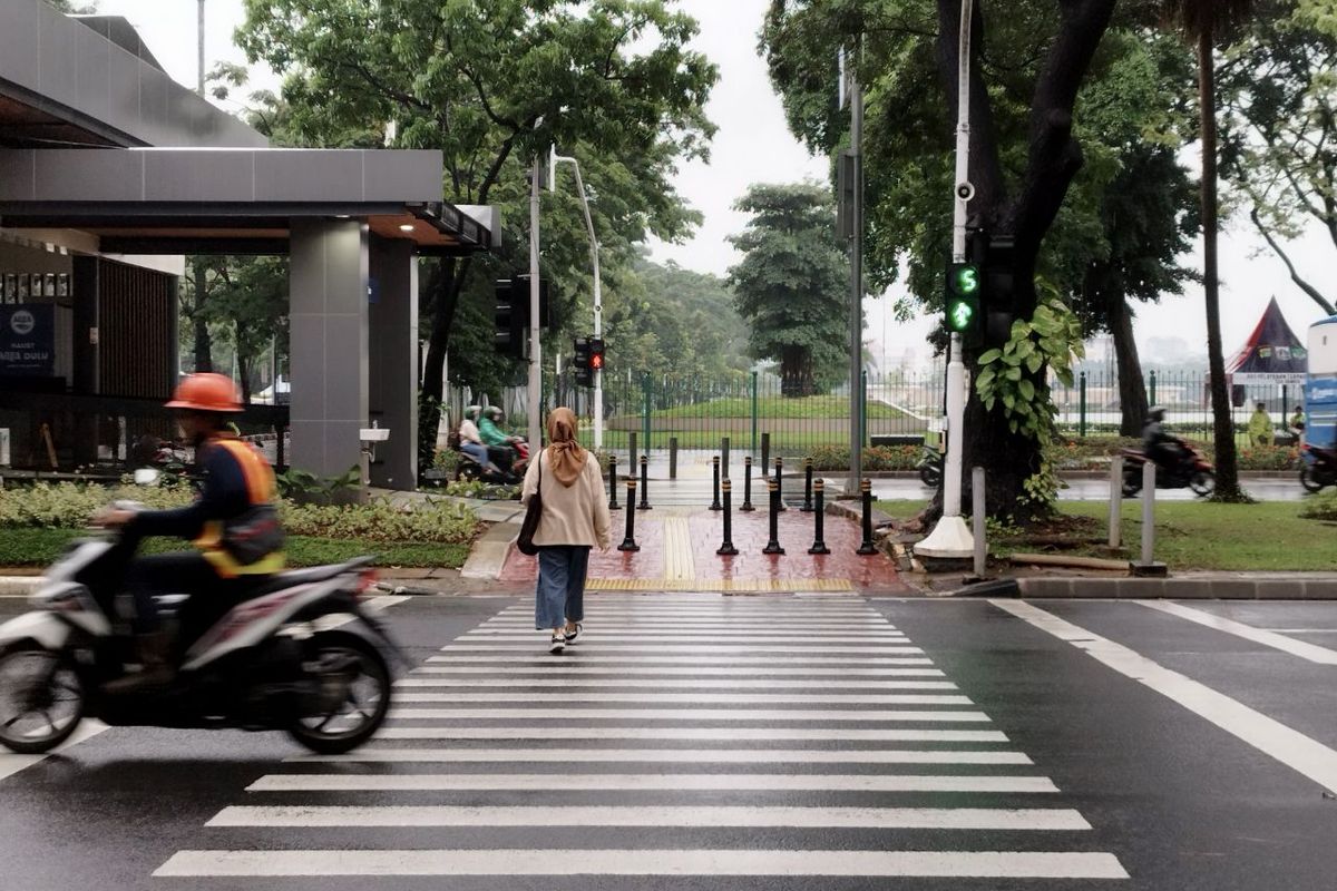 Pengendara motor menerobos lampu merah saat pejalan kaki sedang menyeberang di zebra cross Halte Balai Kota, Jakarta Pusat, pada Minggu (26/2/2023).