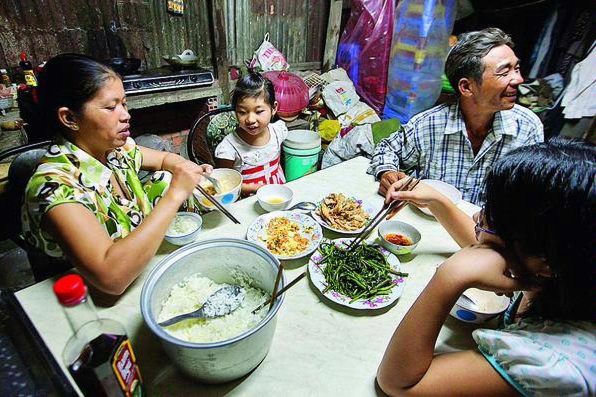 Seorang ibu  bernama Vo Thi Quan (44), di sebelah kiri; suaminya, Hanh (46); dan dua putri mereka sedang menyantap makan malam pada 11 April lalu di rumah mereka di Thuan Thanh, Provinsi Long An, Vietnam. Naiknya harga-harga komoditas pangan membuat sejumlah warga dunia kini mengalami kelaparan.