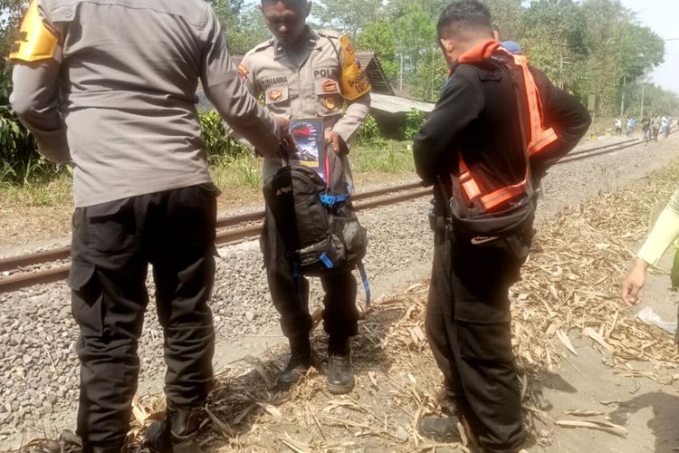 Polisi mengambil tas yang ditemukan di pinggir rel kereta api tidak jauh dari lokasi jasad siswi SMK yang tertabrak kereta api di Desa Kendalrejo, Kecamatan Talun, Kabupaten Blitar, Rabu (18/10/2023) pagi.
