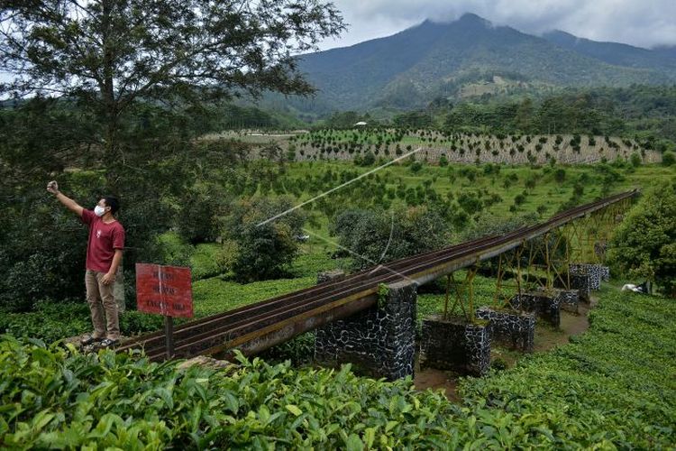 Pengunjung berswafoto di jembatan irigasi air peninggalan zaman kolonial Belanda, kawasan Perkebunan PTPN VIII Dayeuhmanggung, Cilawu, Kabupaten Garut, Jawa Barat, Jumat (22/01/2021). Jembatan irigasi air sepanjang 200 meter yang dibangun pada tahun 1913 oleh kolonial Belanda tersebut menjadi daya tarik wisatawan dengan suasana perkebunan teh dan pemandangan gunung Cikuray (ANTARA FOTO/Candra Yanuarsyah/agr/rwa).