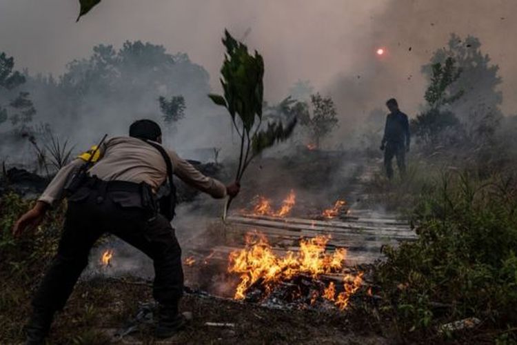 Seorang polisi berusaha memadamkan api yang menyala di suatu lahan di Palangkaraya, 14 September 2019. 