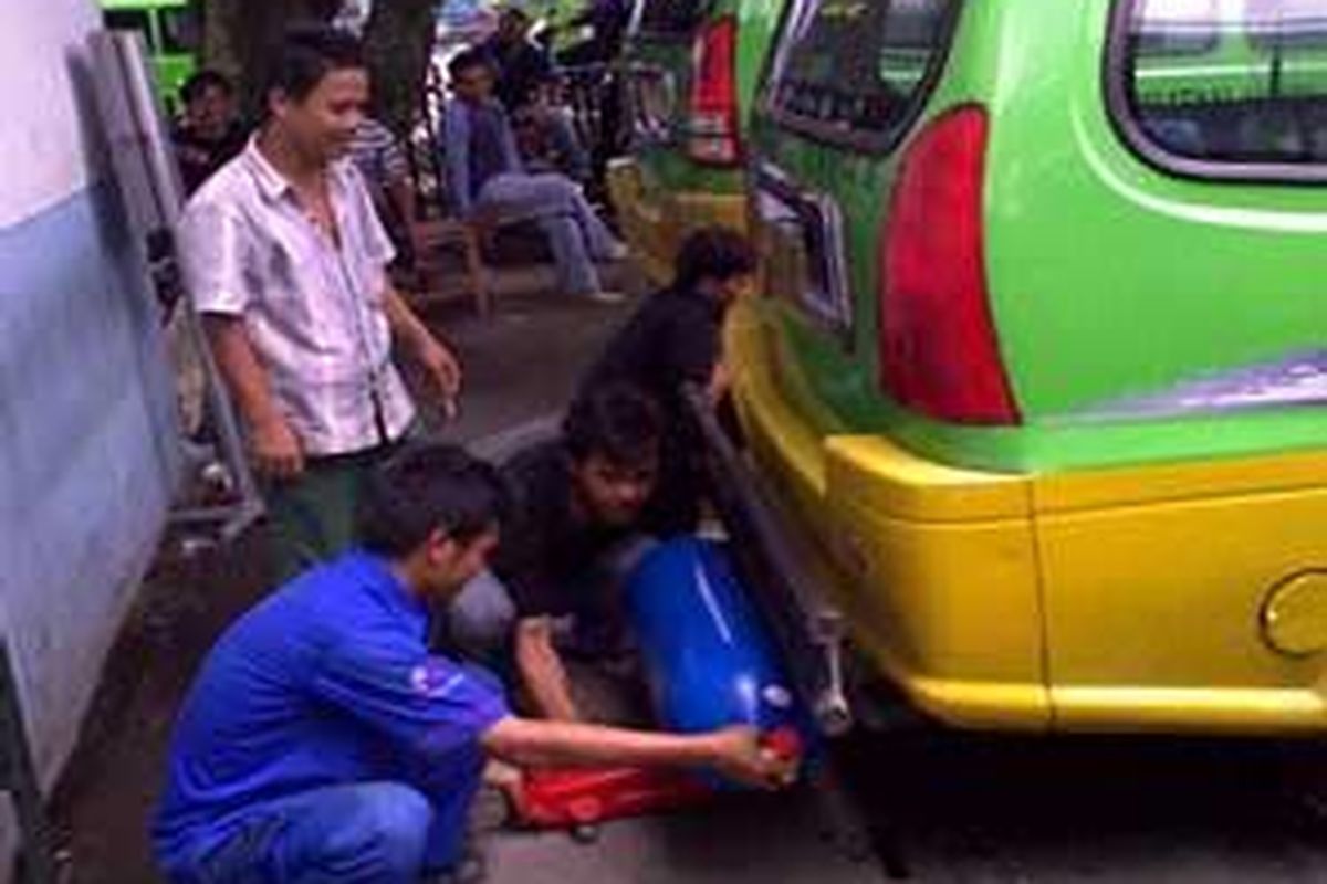 Agus, salah seorang sopir angkot di Bogor, menonton saat teknisi PT Bina Tera Jasindo memasang tabung gas di bagian belakang bawah angkotnya, Kamis (19/11). Ada tujuh angkot siang itu yang menunggu giliran pemasangan converter kit yang memungkinkan angkot menggunakan bahan bakar gas (BBG).