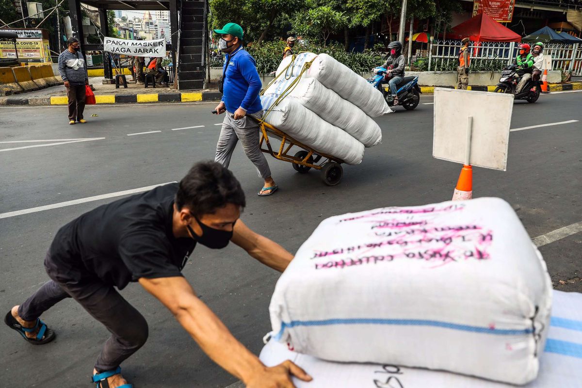 Pekerja menggunakan masker membawa karung berisi pakaian melintas di Tanah Abang di Jakarta Pusat, Senin (14/9/2020). PSBB kembali diterapkan tanggal 14 September 2020, berbagai aktivitas kembali dibatasi yakni aktivitas perkantoran, usaha, transportasi, hingga fasilitas umum.