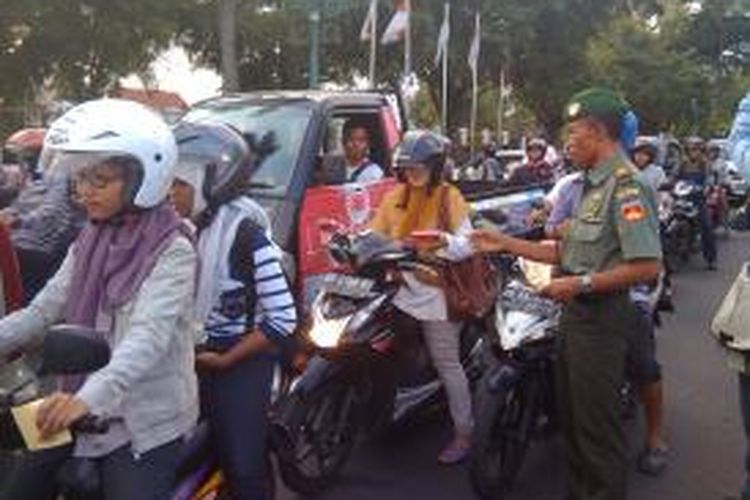 Salah satu pwrsonil TNI membagikan stiker kita semua bersaudara kepada warga yang melintas di titik nol Km