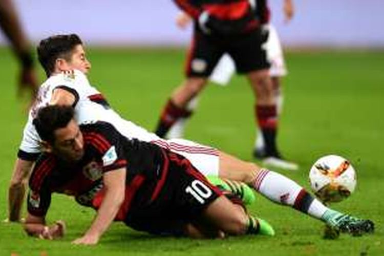 Robert Lewandowski (putih) berduel dengan Hakan Calhanoglu saat Bayern Muenchen melawan Bayer Leverkusen pada lanjutan Bundesliga di Stadion BayArena, Sabtu (6/2/2016).