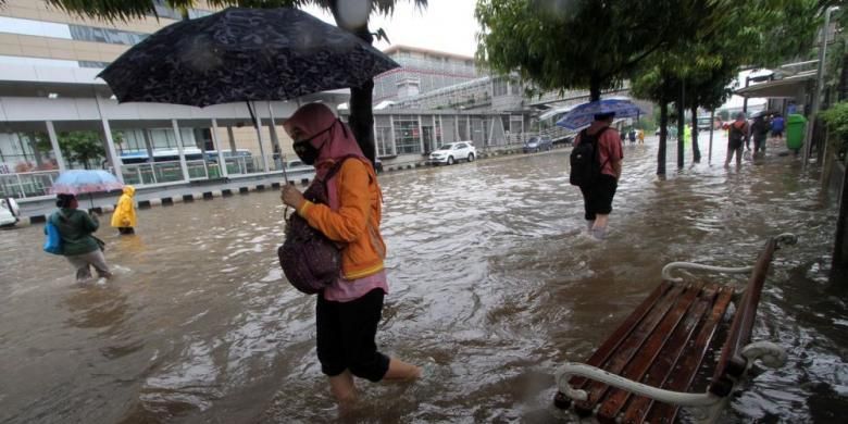 Warga melintasi trotoar yang terendam banjir di Jalan MH Thamrin, Jakarta Pusat, Senin (9/5/2015). Curah hujan yang tinggi mengakibatkan sejumlah tempat di ibu kota terendam banjir.