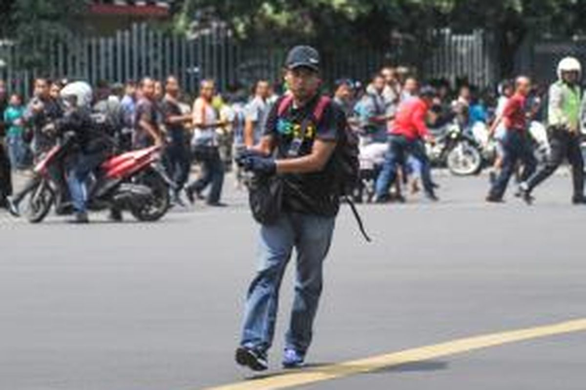 Foto ini dirilis oleh agensi berita China Xinhua, seorang pria tak dikenal dengan senjata berjalan dengan latar belakang kerumunan orang, di kawasan Jalan MH Thamrin, dekat pusat perbelanjaan Sarinah, Jakarta, 14 Januari 2016.