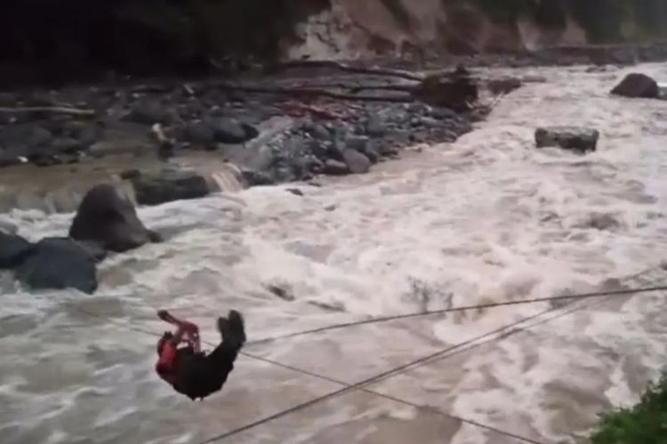 Petugas dari Kantor SAR Padang melintasi lintasan tali yang membentang sepanjang 50 meter untuk mengevakuasi dua korban yang hanyut terbawa banjir bandang di aliran Sungai Silaing Bawah, Kabupaten Padang Panjang, Sumatera Barat, Sabtu (29/11/2025). 