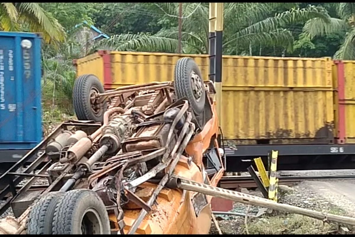 Sebuah kereta api melintas tepat di sisi truk CPO yang terjungkal di perlintasan kereta api Penanggiran Muara Enim