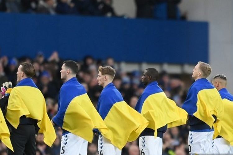 Para pemain Everton membawa bendera Ukraina ketika memasuki lapangan pada pertandingan pekan ke-27 Liga Inggris kontra Manchester City yang dihelat di Stadion Goodison Park, Minggu (27/2/2022).