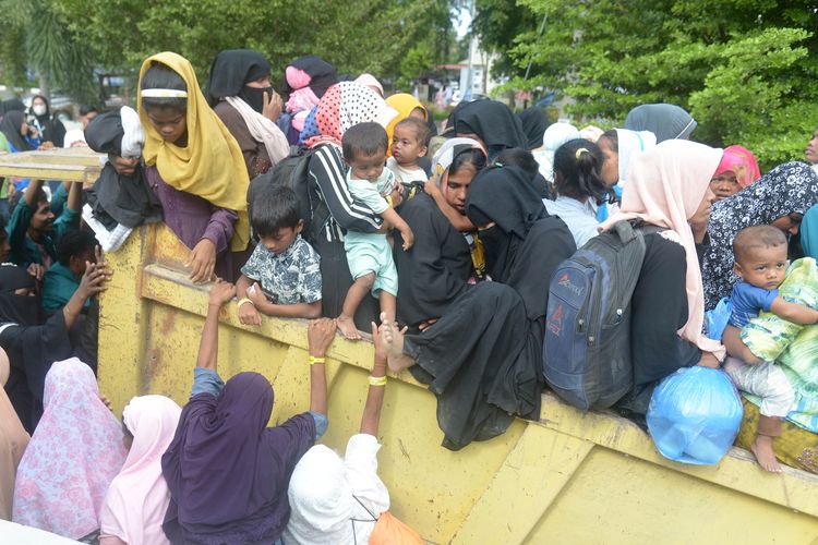 Mahasiswa bersama polisi membantu menaikan sejumlah imigran etnis Rohingya ke truk saat berlangsung pemindahan paksa di penampungan sementara gedung  Balai Meuseuraya Aceh (BMA), Banda Aceh, Aceh, Rabu (27/12/2023). Sebanyak 137 pengungsi imigran etnis Rohingya yang ditempatkan di penampungan sementara gedung BMA itu dipindahkan paksa mahasiswa setelah menggelar aksi damai ke kantor Kemenkumham Provinsi Aceh. (ANTARA FOTO/Ampelsa/Spt)