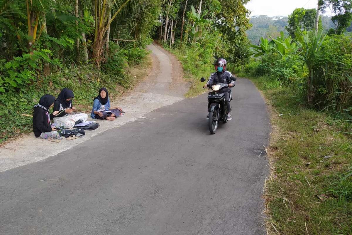 Teara, adik dan kawannya mengikuti kuliah daring di tepi jalan karena sulit sinyal internet, di Desa Kenalan, Kecamatan Borobudur, Kabupaten Magelang.