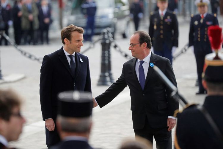 Presiden Perancis Francois Hollande (kanan) menyentuh lengan Presiden terpilih Perancis Emmanuel Macron (kiri), saat mereka berdiri di batu nisan pahlawan tak dikenal di the Arc de Triomphe, Paris, Senin (8/5/2017).  