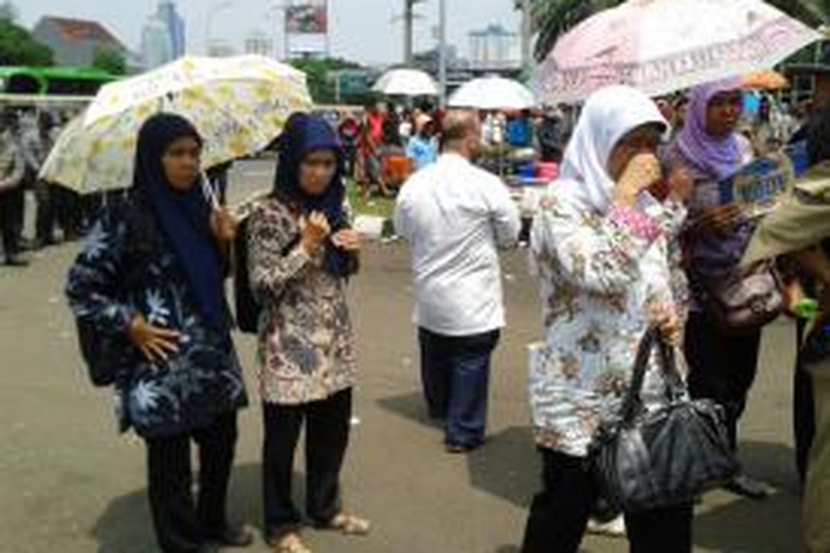 Beberapa tenaga honorer yang berdemo di depang gedung DPR/MPR sambil berteduh di bawah payung,Jumat (14/3/2014)
