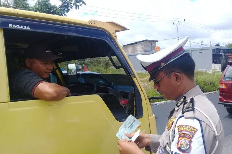 Seorang Polantas Polres Mimika ketika sedang memeriksa surat-surat kendaraan terhadap salah satu pengendara yang belok kiri tanpa mengikuti traffic light, Senin (21/1/2019)