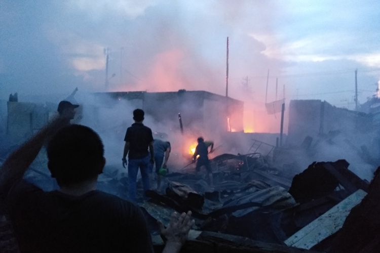 Petugas pemadam kebakaran bersama warga masih berupaya memadamkan api yang membakar rumah warga di Jalan Sentosa Lama, Kelurahan Sei Kera Hulu, Kecamatan Medan Perjuangan, Senin sore tadi (21/10/2019). Warga bingung akan bermalam di mana karena harta bendanya habis terbakar.