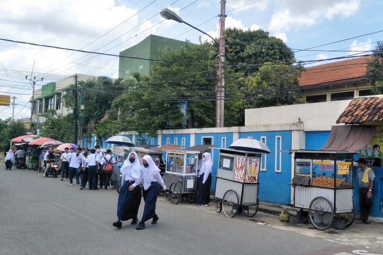 Siswa berpakaian putih biru membeli jajanan di depan SMPN 3 Depok, Senin (24/1/2022).