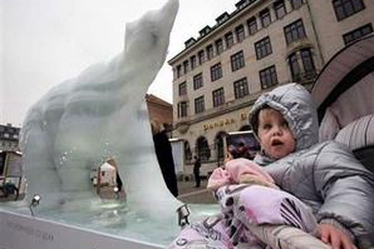 Foto anak kecil di samping patung es beruang kutub yang tengah meleleh (lambang pemanasan global) di tengah Copenhagen, Denmark, sehari sebelum pertemuan tingkat tinggi perubahan iklim, Dec. 6, 2009, 