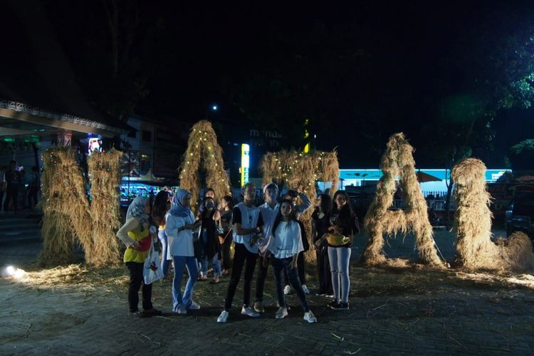 Sejumlah warga berfoto di instalasi jerami bertuliskan Natal dalam perayaan Natal Kreatif Siantar di Lapangan Haji Adam Malik, Pematangsiantar, Selasa (25/12/2018).